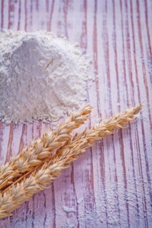 Ears of wheat and flour on a vintage wooden board Food and drink concept