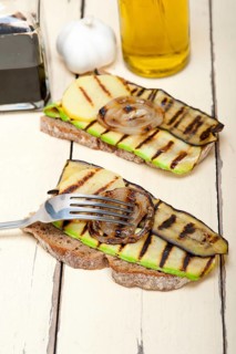 Grilled vegetables on rustic bread over wood table
