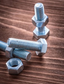 Group of stainless steel threaded bolts and nuts on vintage wooden board construction concept