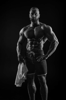 Silhouette of a strong bodybuilder. Confident young fitness athlete with a powerful body and perfect abs. Black and white photography. Dramatic light. Mixed media