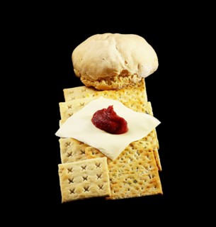 Bread and crackers with cheese and tomato on black background