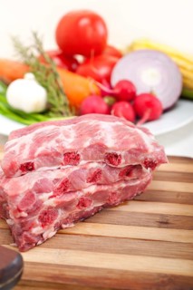 Chopping fresh pork ribs with vegetables and herbs ready to cook