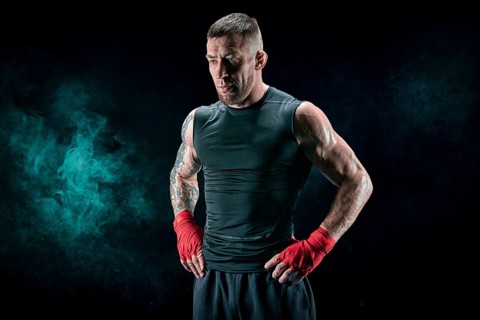 Kickboxer in red bandages stands against a background of smoke. The concept of mixed martial arts. MMA