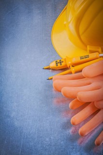 Electricians rubber gloves building helmet electric tester on scratched metallic background electricity concept
