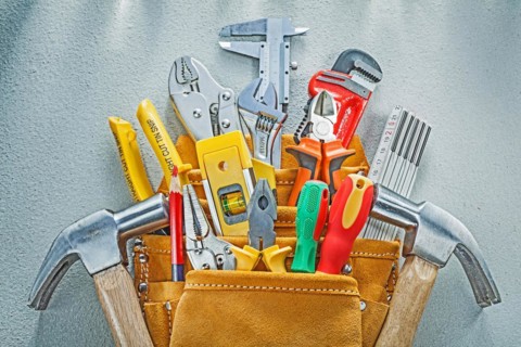 Composition of construction tooling in tool belt on concrete background