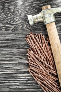 Stack of copper nails claw hammer on wooden board