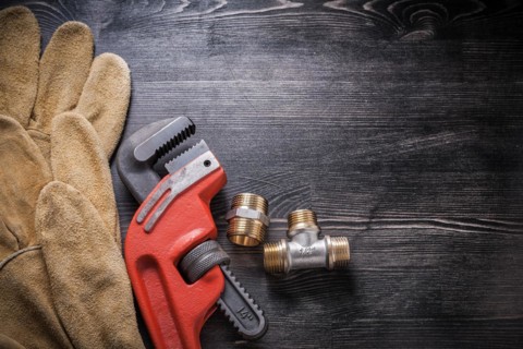 Adjustable wrench plumbing fixtures protective gloves on wooden board