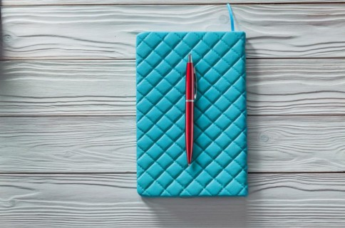Blue classic soft notepad and red ball point pen on vintage painted wood boards