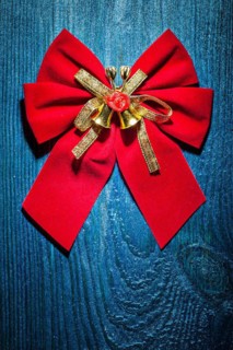 Beautiful red Christmas bow with gold ribbon and bells on an old blue lacquered wooden board