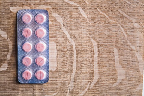 Blister pack with rose medical pils on wooden board with cpyspace