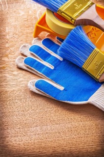 Paint tray Brushes Adhesive tape and protective gloves on wooden panel Construction concept