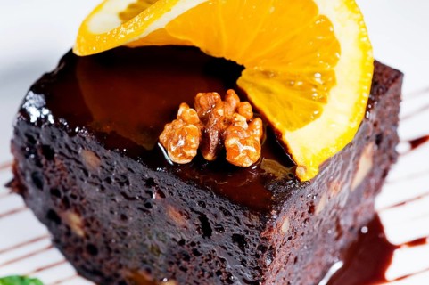 Fresh baked delicious chocolate and walnuts cake with slice of orance on top