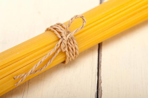 Italian pasta spaghetti tied with a rope on a rustic table