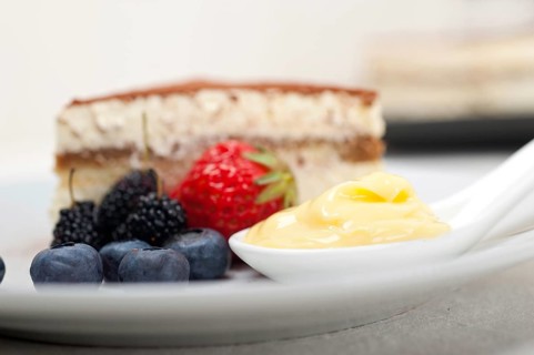 Classic Italian tiramisu dessert with berries and custartd pastry cream on side