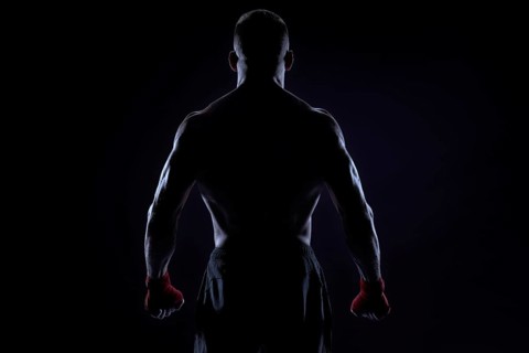 Kickboxer in red bandages posing on a blue background. Back view. The concept of mixed martial arts. MMA