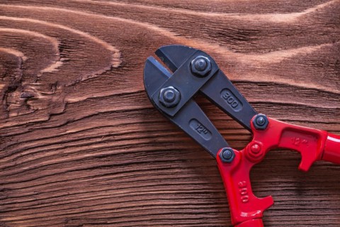 Black and red bolt cutters on wooden panel Construction concept