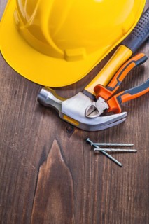 Claw hammer pliers nails yellow helmet on vintage wooden board construction concept