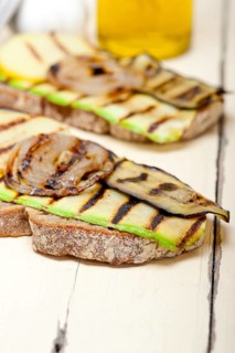 Grilled vegetables on rustic bread over wood table