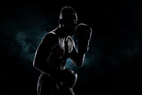 Kickboxer in black gloves posing on a background of smoke. The concept of mixed martial arts. MMA