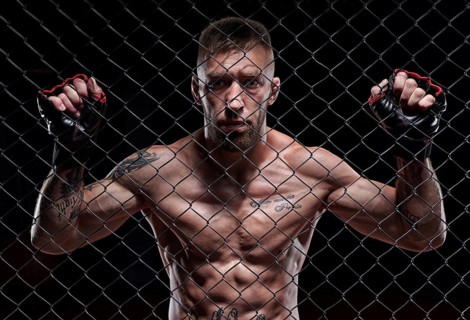Dramatic image of a mixed martial arts fighter standing in an octagon cage. The concept of sports
