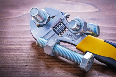 Adjustable spanner Steel threaded bolts and nuts on wooden plates Design concept