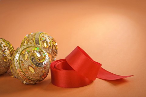 Golden Christmas baubles and red bow on a brown background