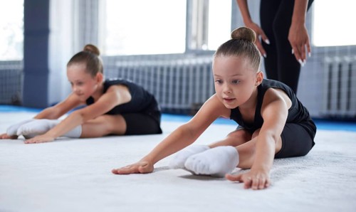 Training in the gym class. A group of children under the guidance of a coach perform exercises. Gymnastics concept. Mixed media