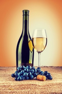 Bottle of wine and wineglass with branch of grape on burlap instagram style