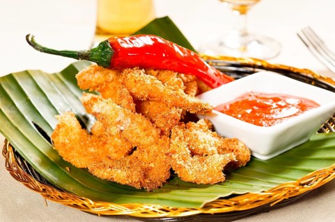 Fresh deep fried buffalo shrimps with a red chili pepper on top and sweet and sour sauce dip on side