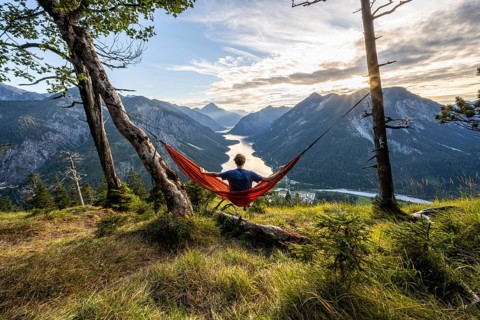 Young man sitting in an orange hammock