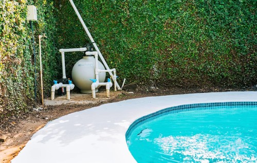 Pool pump with sand filter installed near of swimming pool. Home swimming pool filter and treatment plant installed. Pool purification and maintenance system