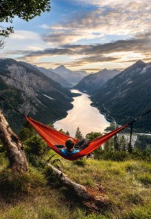 Young man sitting in an orange hammock