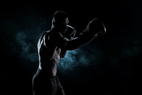 Kickboxer in black gloves posing on a background of smoke. The concept of mixed martial arts. MMA