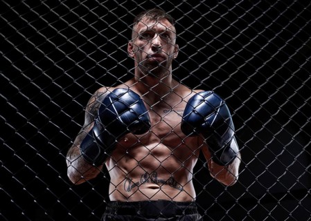 Dramatic image of a mixed martial arts fighter standing in an octagon cage. The concept of sports