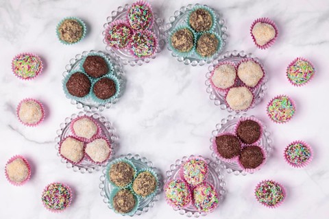Light and dark rum balls arranged in a circle on and next to glass plates