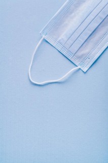 Disposable face mask on blue background with copy area vertical version