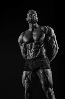 Silhouette of a strong bodybuilder. Confident young fitness athlete with a powerful body and perfect abs. Black and white photography. Dramatic light. Mixed media