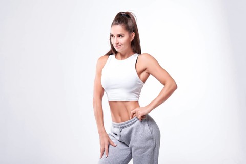 Young white fitness woman wearing sportswear standing over white wall background. Fitness concept. Mixed media