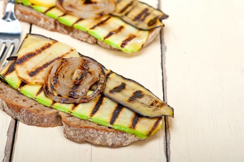 Grilled vegetables on rustic bread over wood table