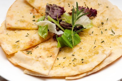 Fresh healthy garlic pita bread pizza with salad on top