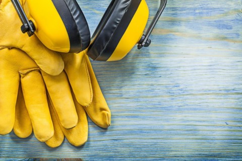 Earmuffs protective spectacles leather gloves building helmet on wood board construction concept