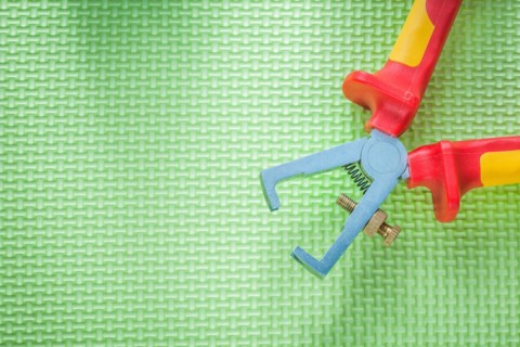 Insulated wire strippers on green background electricity concept