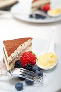 Classic Italian tiramisu dessert with berries and custartd pastry cream on side