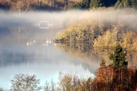 The Steinbach Dam near the national park community of Langweiler on the edge of the Hunsrueck-Hochwald National Park with fog on an early winter morning