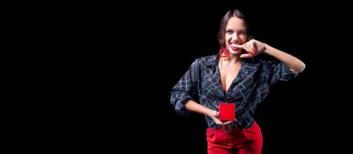 Sexy tall brunette holding a red jewelry box. She bites her finger erotically. The concept of gifts and congratulations.