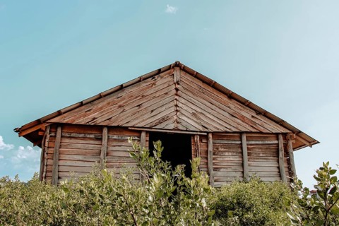Wooden hut with a peaked roof against a blue sky. Kampot