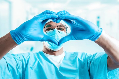 Portrait of a doctor in a hospital. He folded his hands in the shape of a heart. Medicine concept.