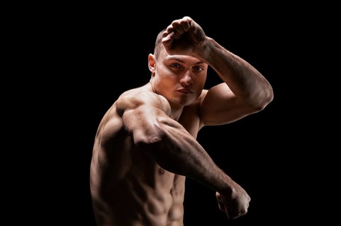 Professional boxer posing in the studio. He stands in front of the camera and elbows. The concept of sport