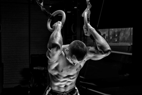 Athlete does warm-up on gymnastic rings. The concept of sport and healthy lifestyle.