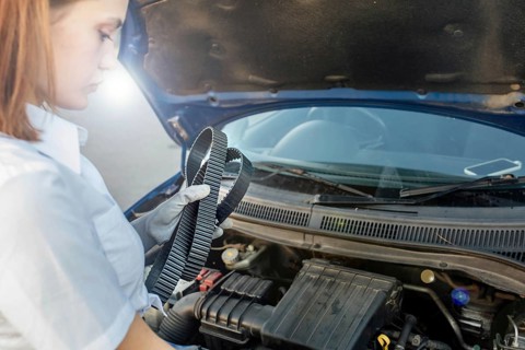 Young beautiful and hot woman auto mechanic holding a timing belt in her hands
